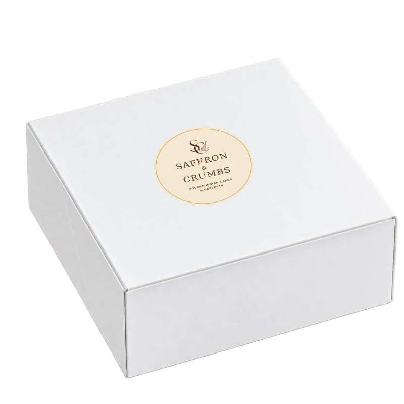 Plain white 8 by 8 inch craft box with the Saffron and Crumbs SC and whisk logo on its sticker